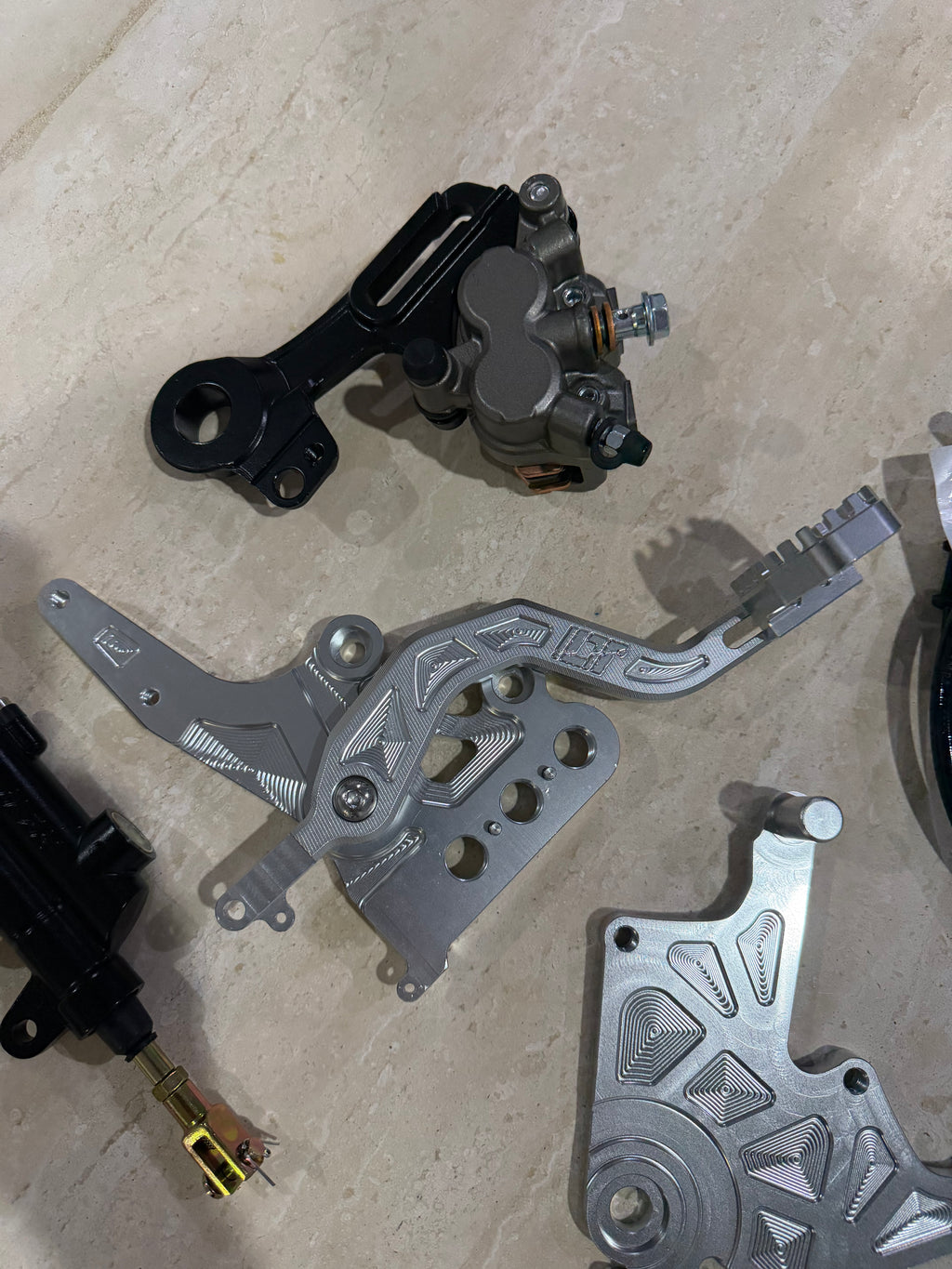 E-moto foot brake kit components with black caliper, silver pedal bracket and mounting plate