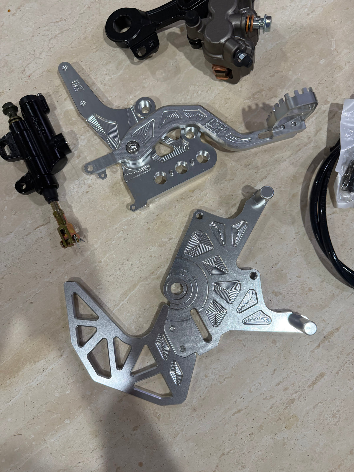 E-moto foot brake kit laid out with caliper, master cylinder, foot pedal and rotor guard
