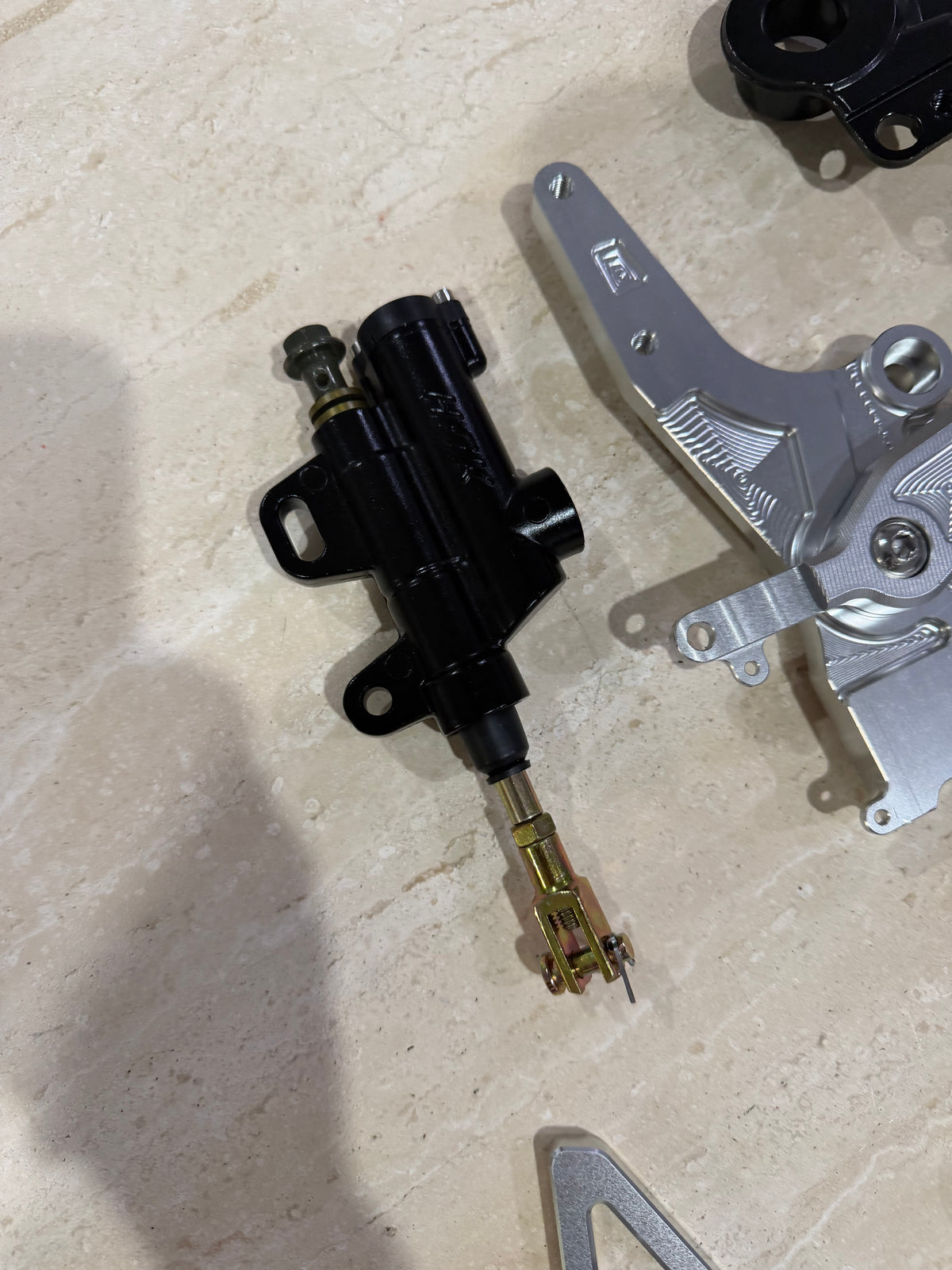 E-moto foot brake master cylinder and machined mounting bracket, close-up detail