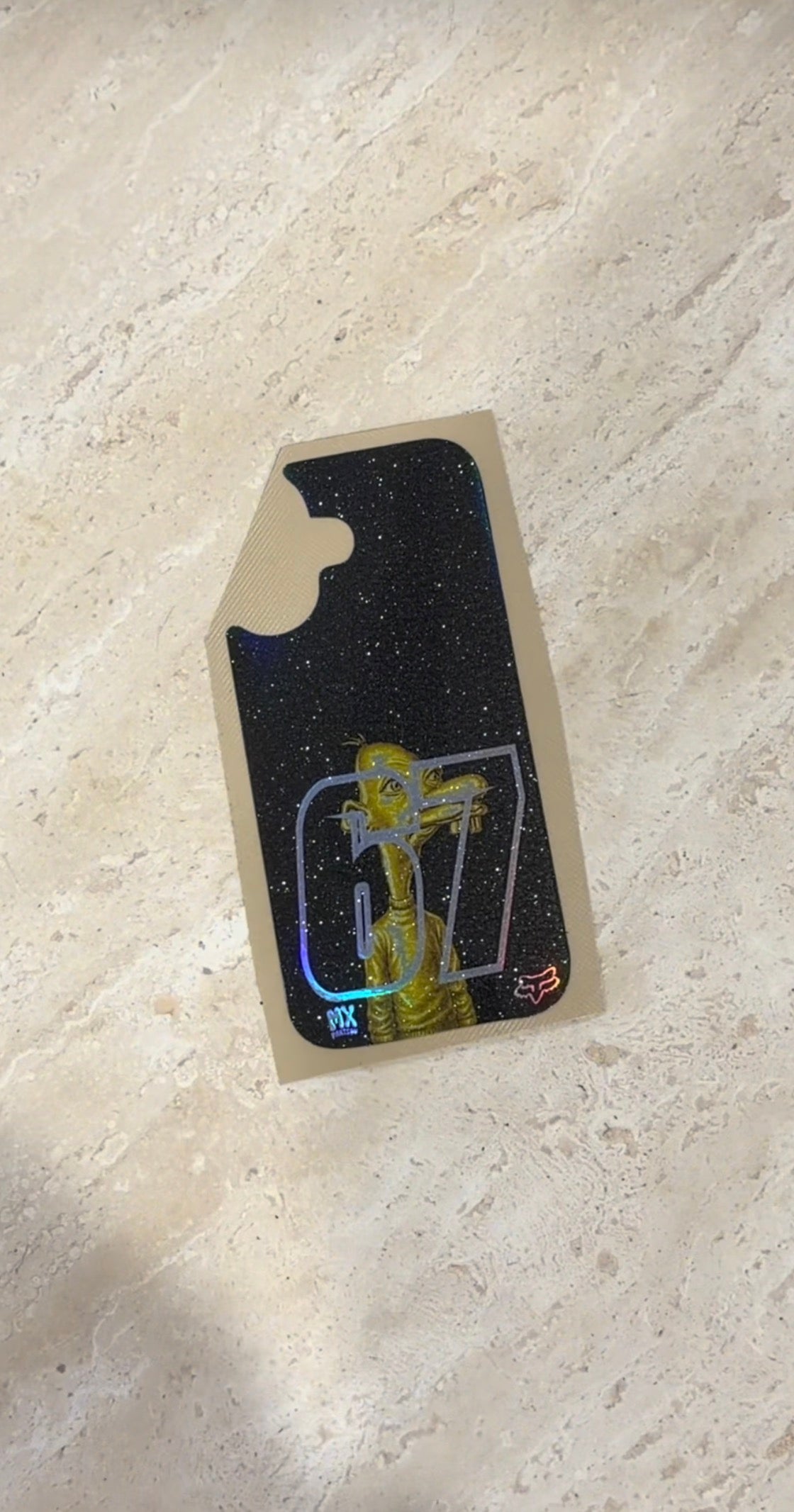 Neegy phone case decal in black with small character graphic shown on backing sheet