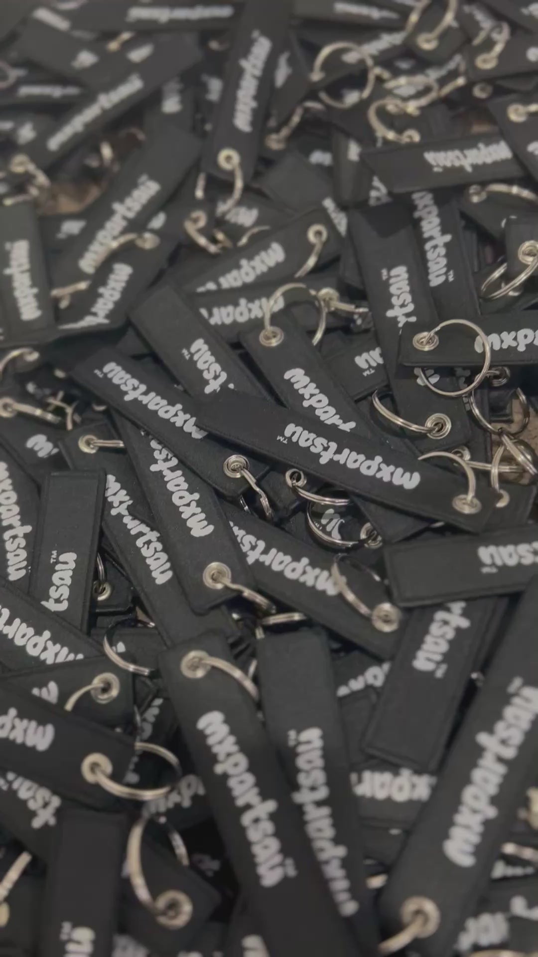 MXPartsAU rubber keychains in black with white branding, shown in a pile